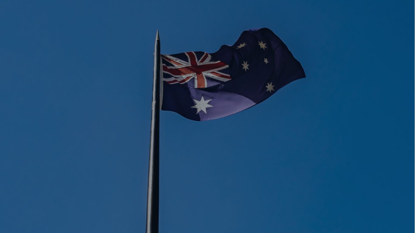 The Australian flag on a blue sky backdrop. Highlighting Clinical trial challenges and complexities in the region.