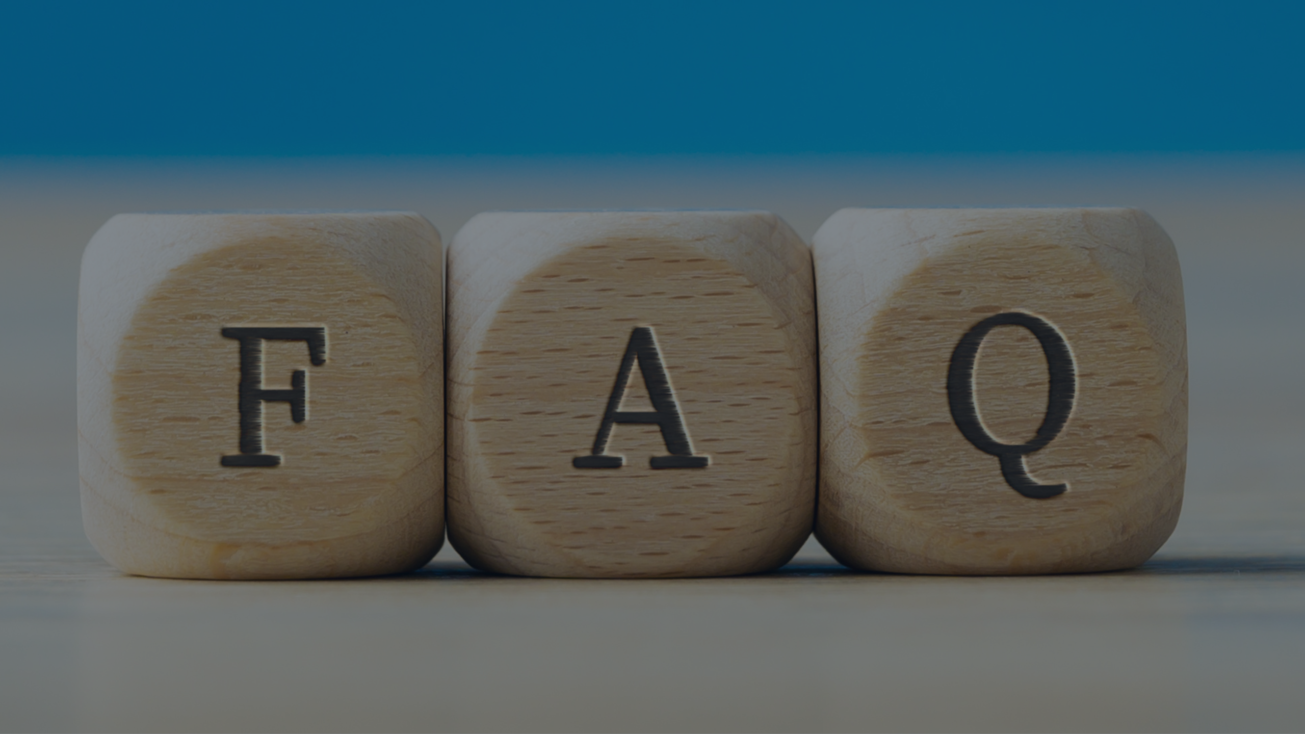 Three wooden letter blocks, FAQ, on a wooden surface against a blue wall for Importer of Record